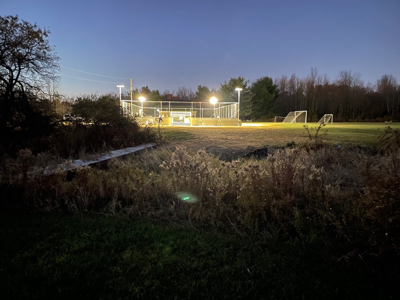 Universal FC soccer field and illuminated fenced court at dusk